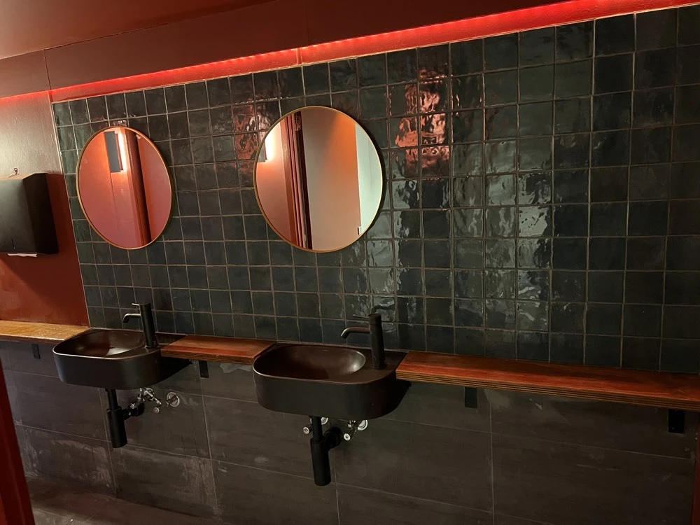 Glossy green bathroom wall tiling at Grouse Melbourne in Fitzroy